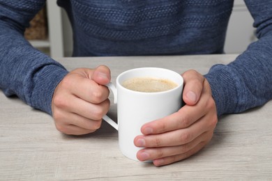 Photo of Man with white mug at wooden table, closeup