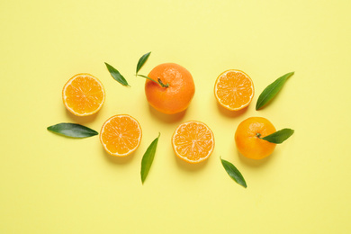 Photo of Flat lay composition with fresh ripe tangerines and leaves on light yellow background. Citrus fruit