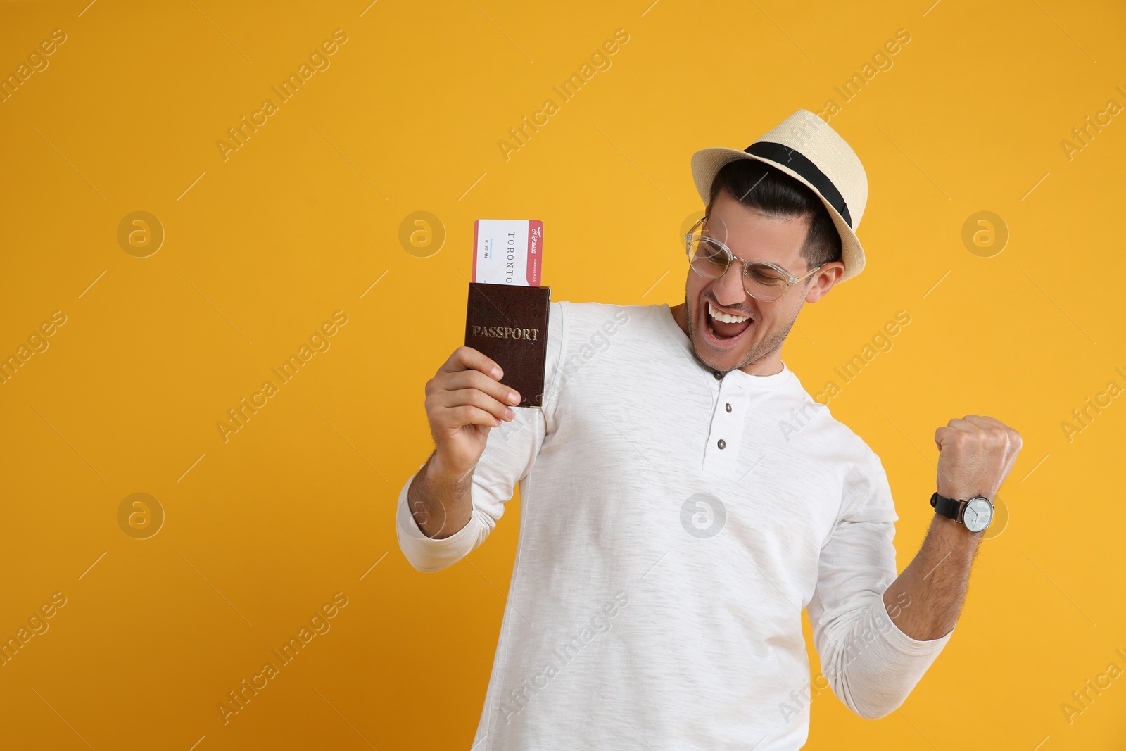 Photo of Excited male tourist holding passport with ticket on yellow background, space for text