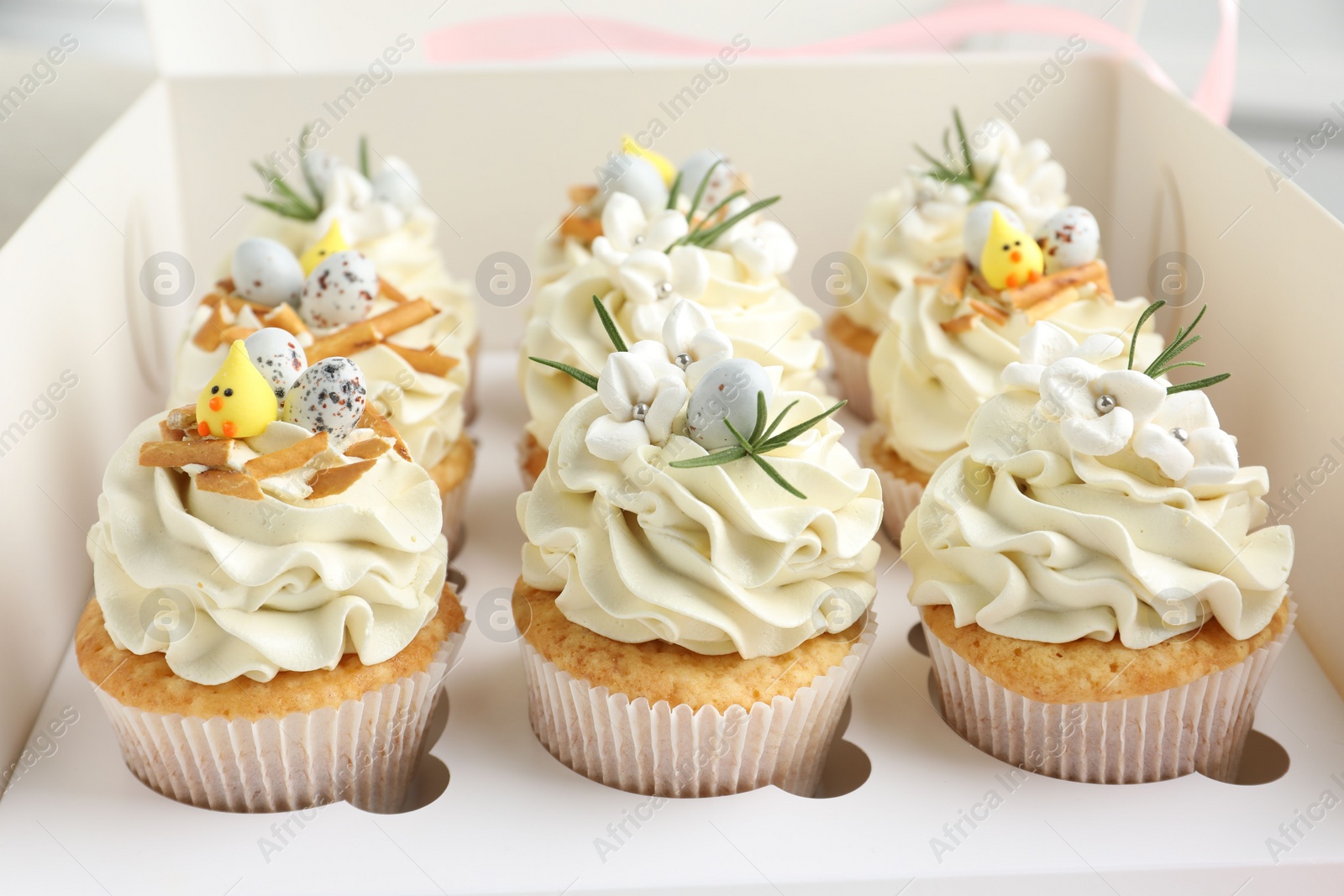 Photo of Tasty Easter cupcakes with vanilla cream in box, closeup