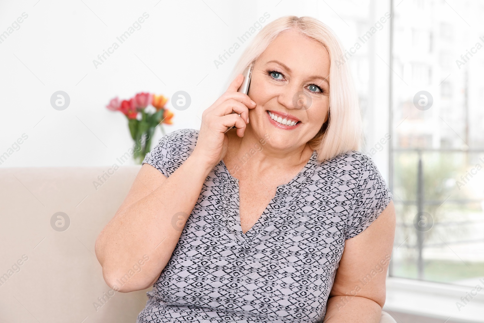 Photo of Mature woman talking on mobile phone at home