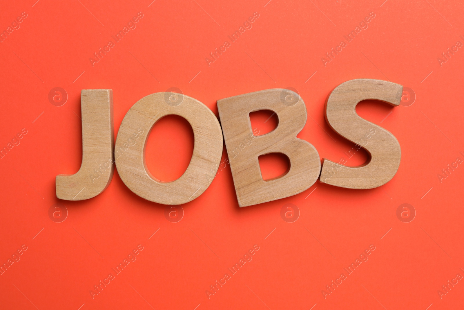 Photo of Word JOBS made with wooden letters on red background, flat lay. Career concept