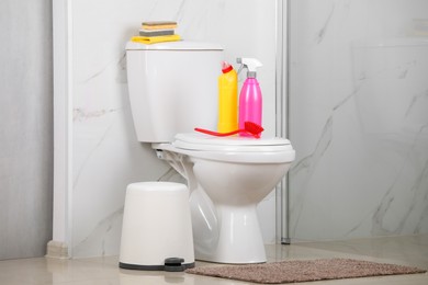 Photo of Cleaning supplies on toilet bowl in bathroom