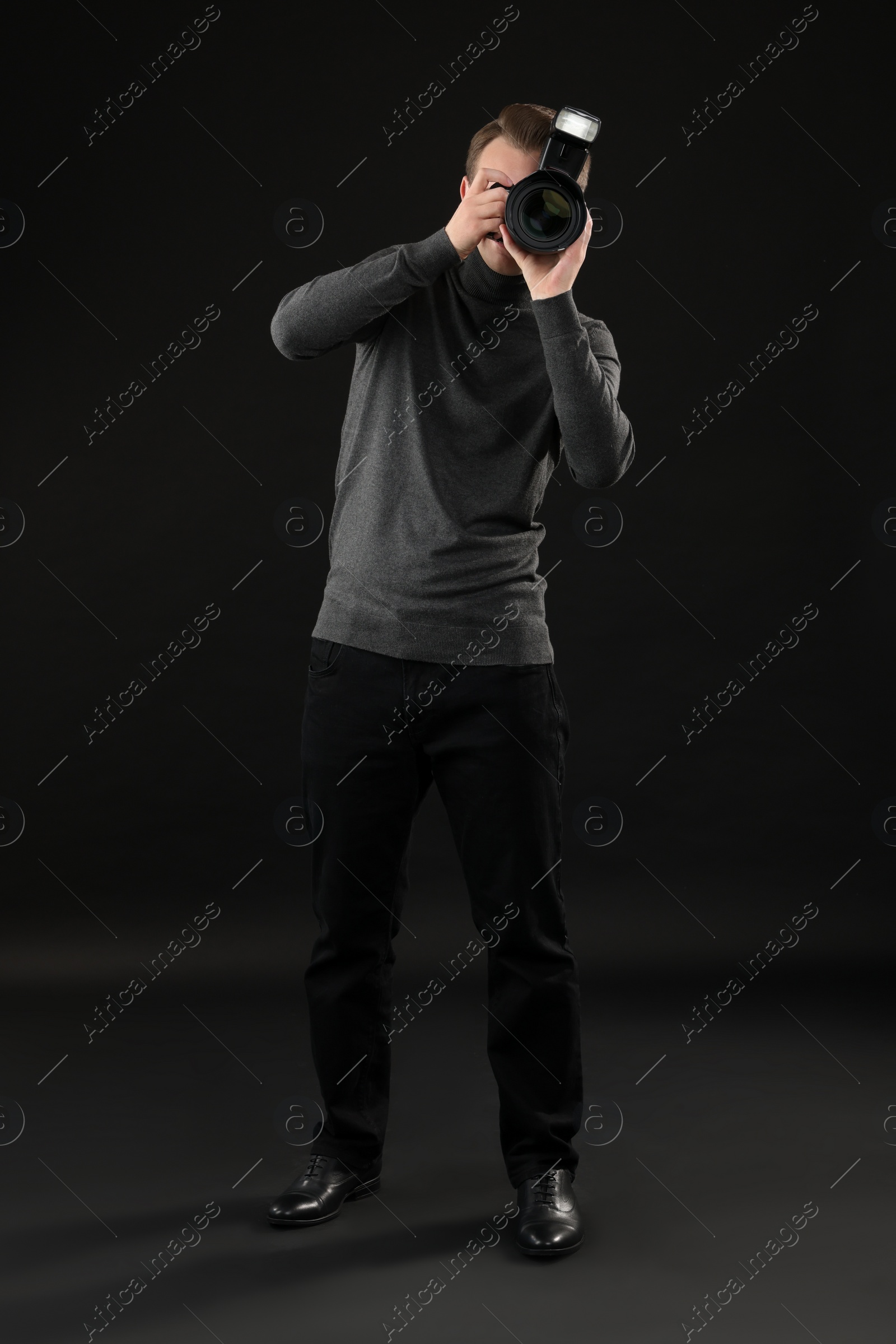 Photo of Professional photographer taking picture on black background