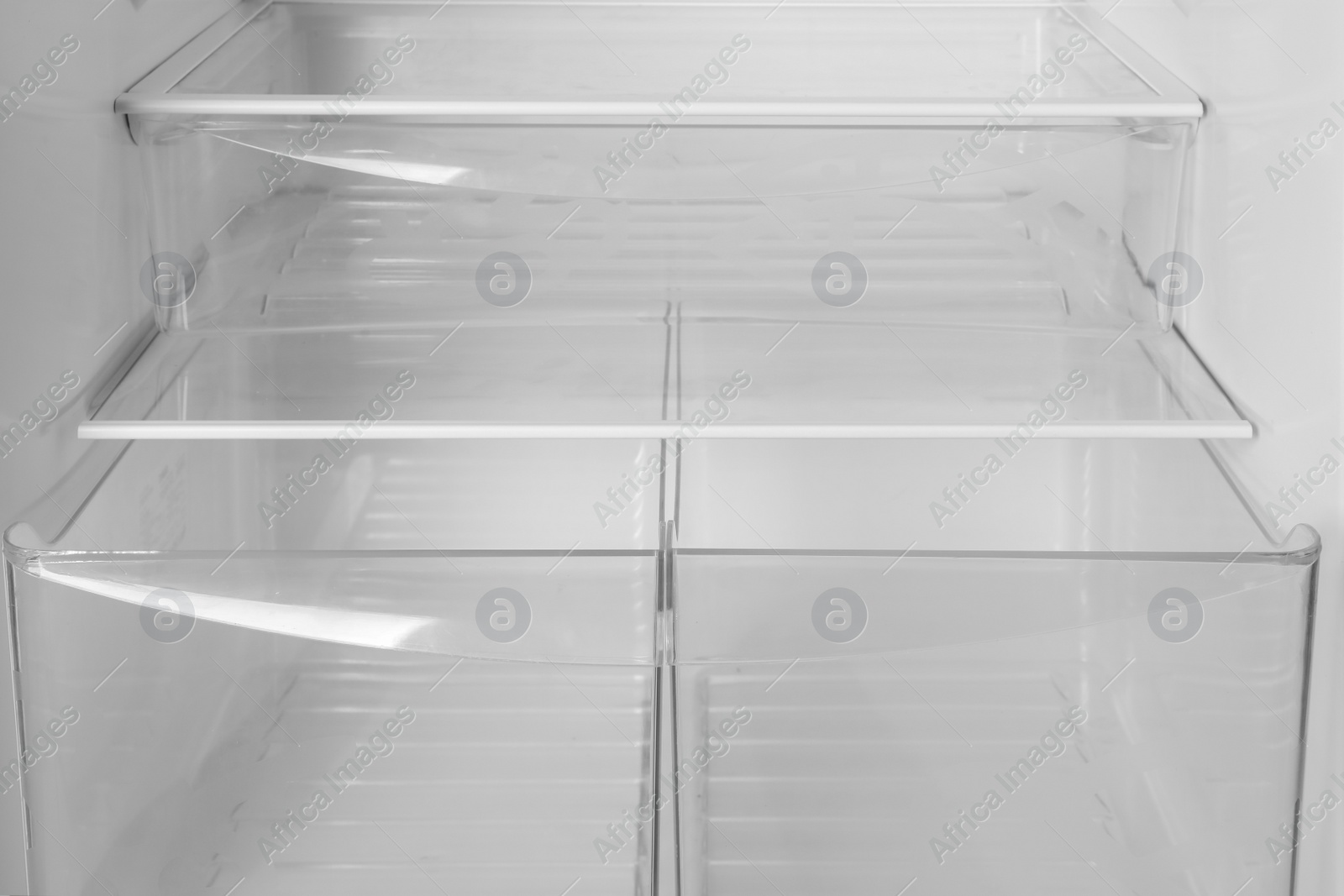 Photo of Modern open refrigerator with empty shelves, closeup