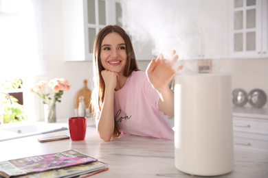 Photo of Woman near modern air humidifier in kitchen