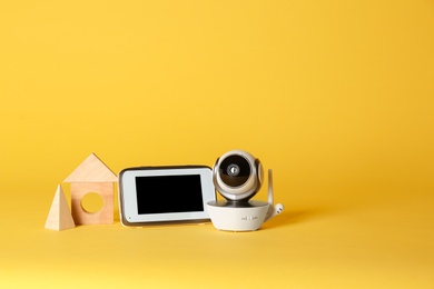 Modern CCTV security camera, wooden blocks and monitor on color background. Space for text