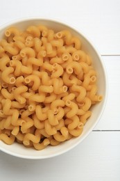 Photo of Raw cavatappi pasta in bowl on white wooden table, top view