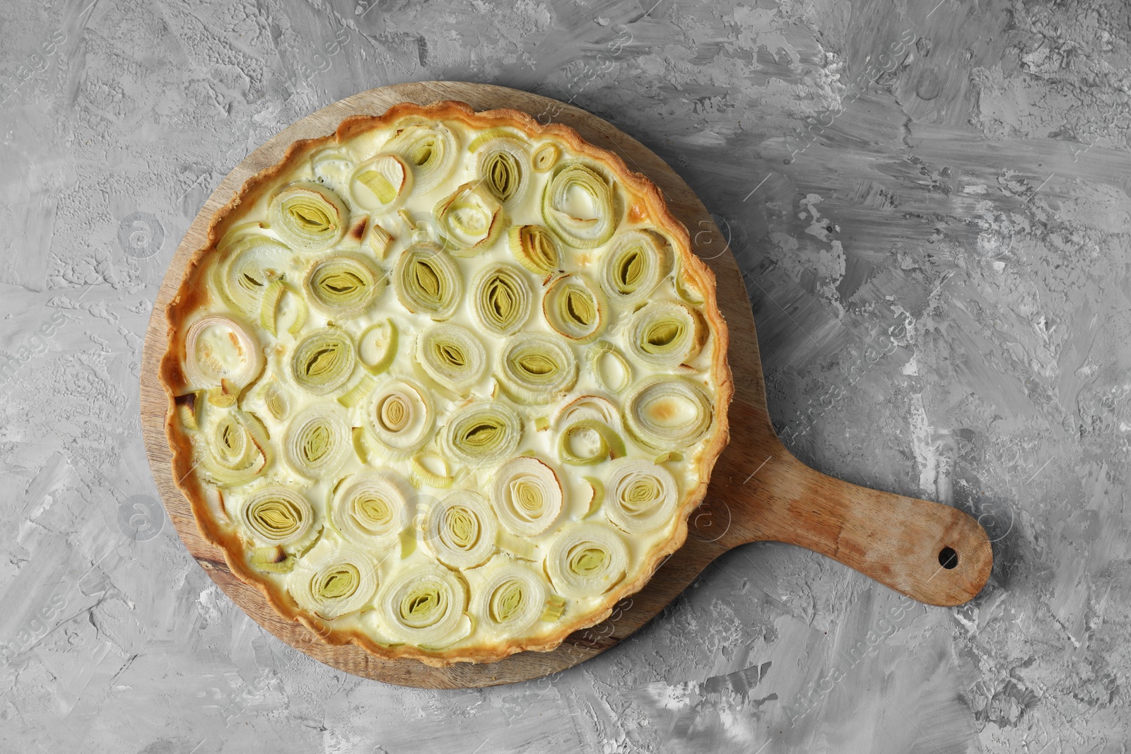 Photo of Freshly baked leek pie on grey textured table, top view