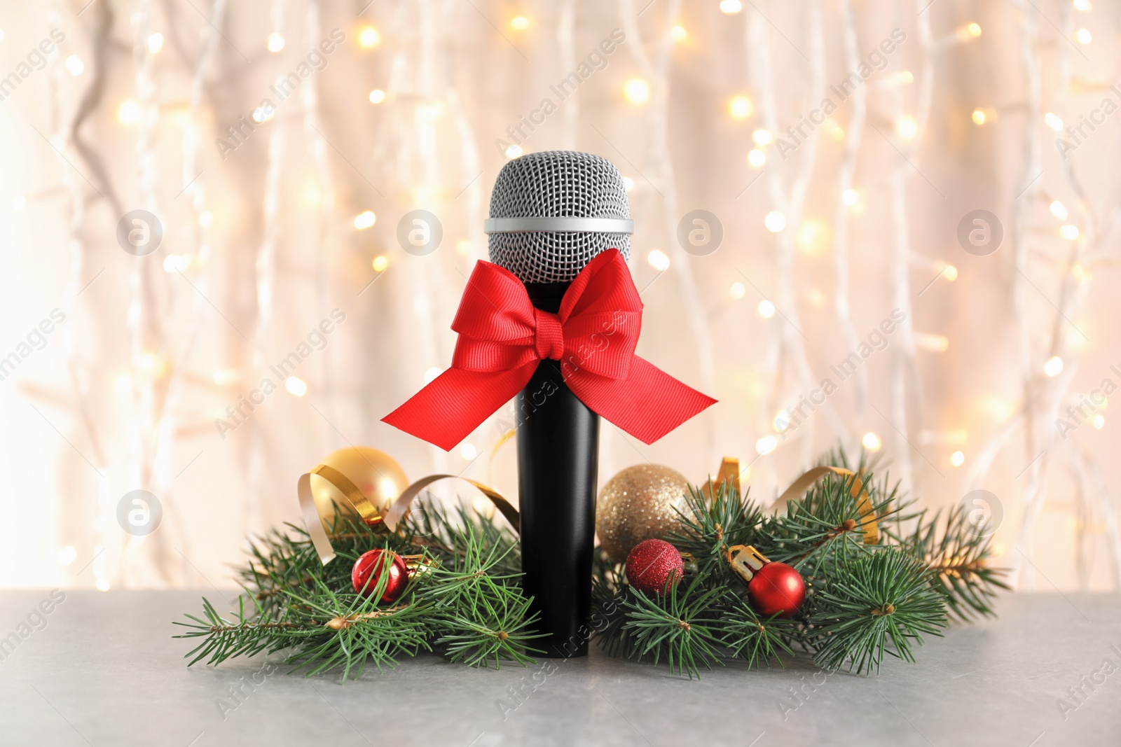 Photo of Microphone with bow and decorations on table against blurred background. Christmas music concept