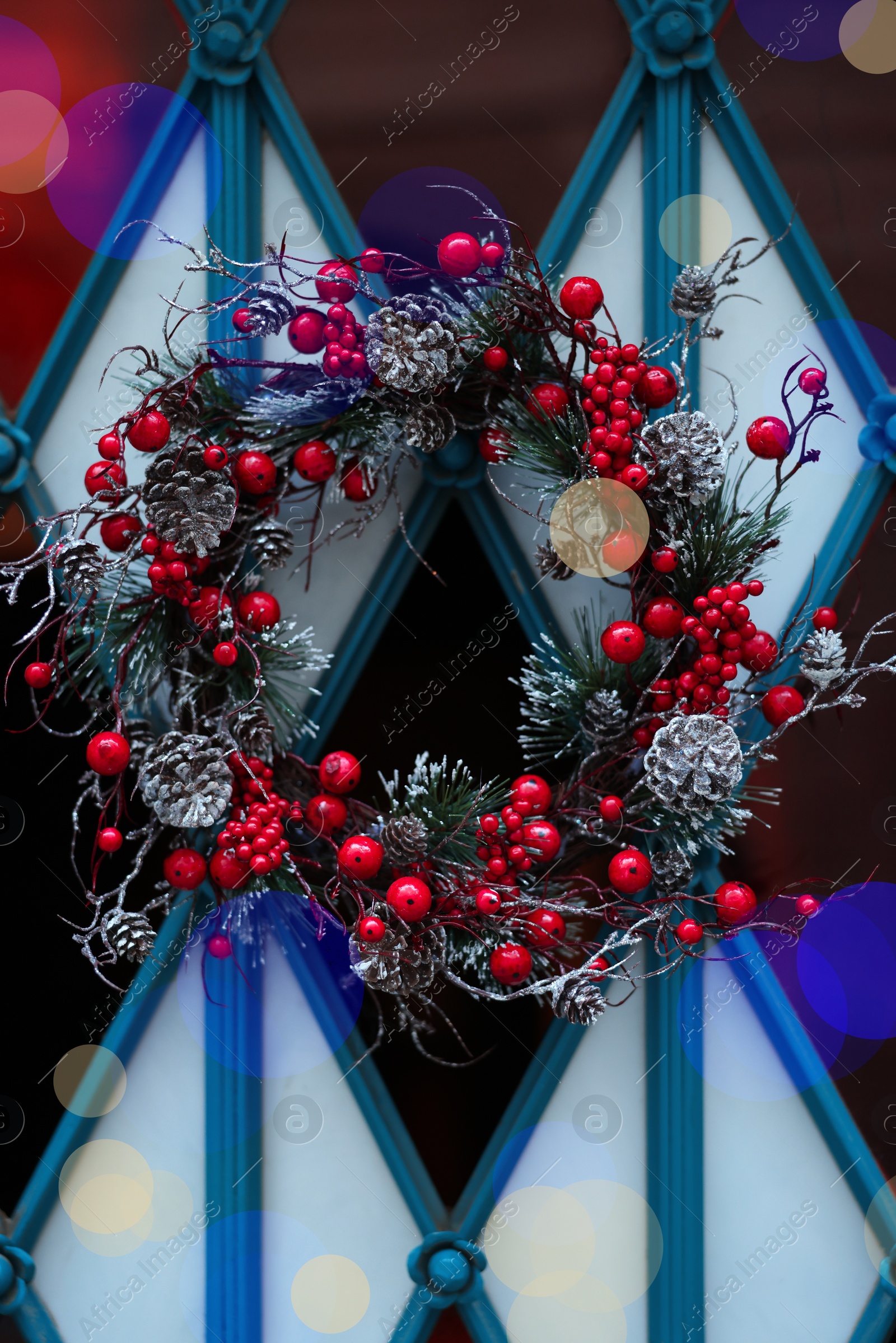 Photo of Beautiful Christmas wreath with berries and cones hanging on door