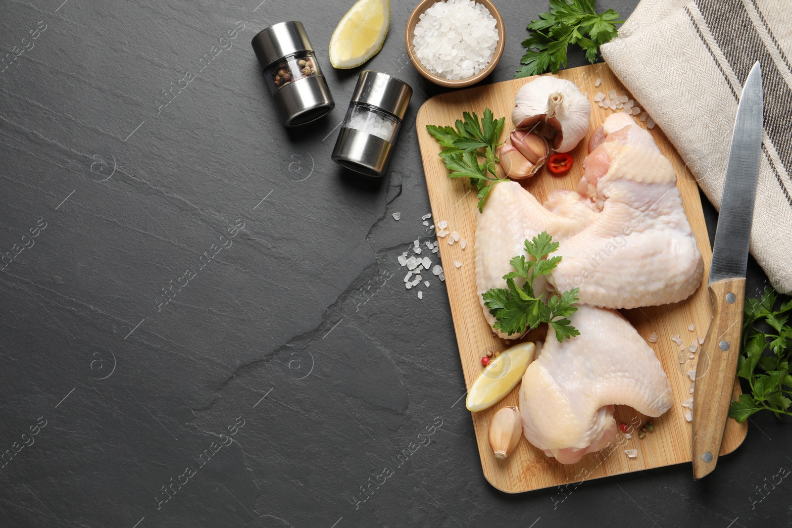 Photo of Flat lay composition with fresh raw chicken wings on black table. Space for text