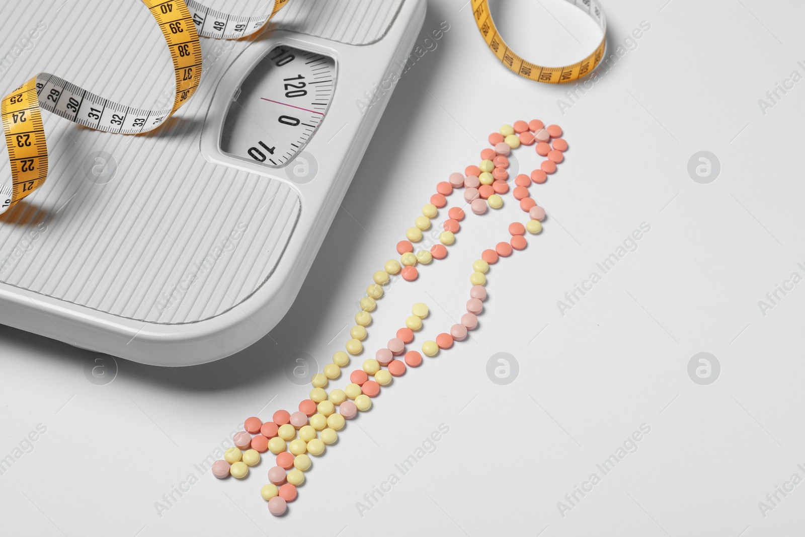 Photo of Composition with slim woman silhouette made of weight loss pills on white background