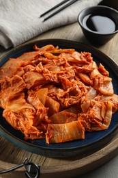 Photo of Delicious kimchi with Chinese cabbage and sauce on wooden tray