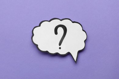 Photo of Paper speech bubble with question mark on violet background, top view