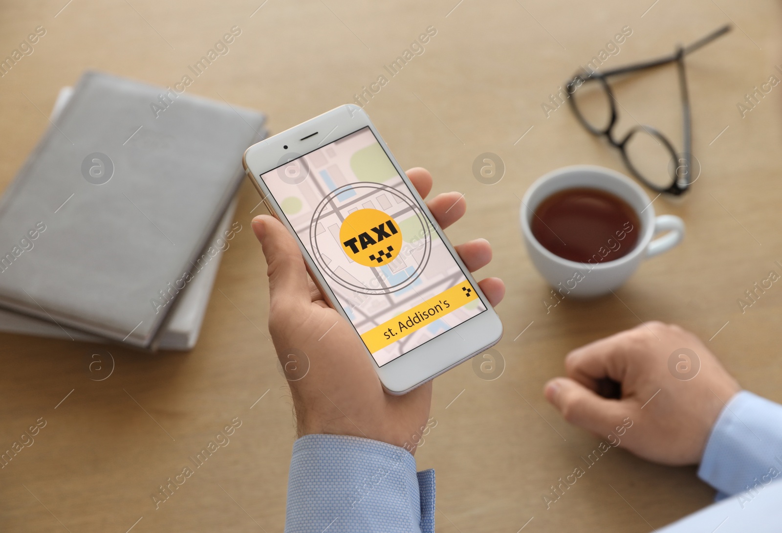 Photo of Man ordering taxi with smartphone at wooden table, closeup