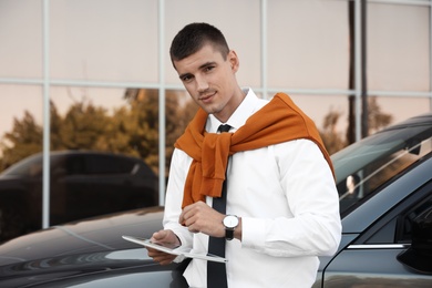Photo of Attractive young man with tablet near luxury car outdoors