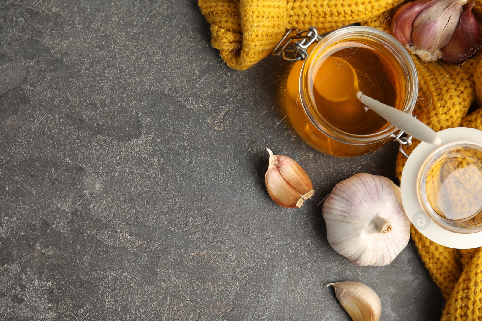 Photo of Flat lay composition with garlic and other cold remedies on grey table. Space for text