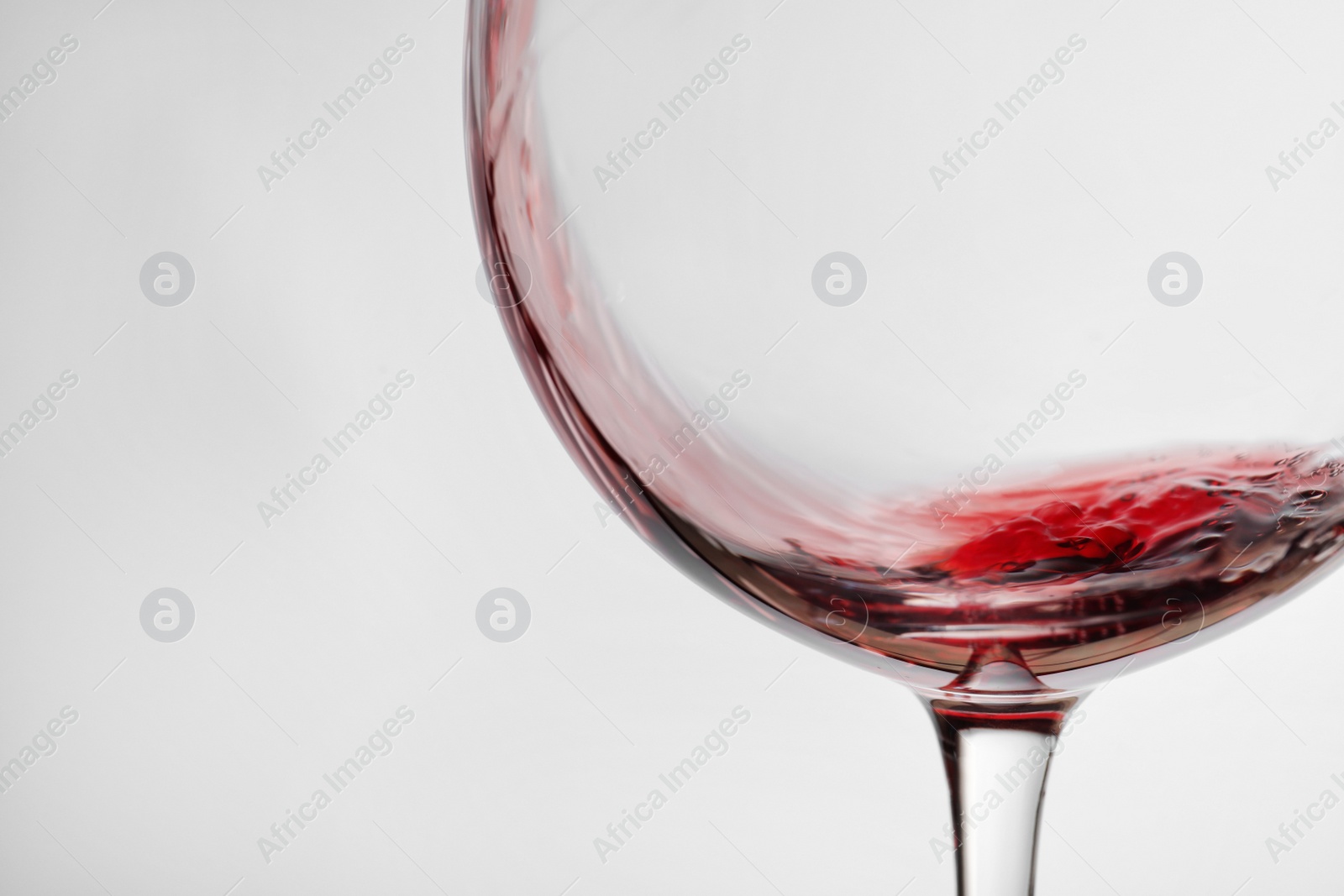 Photo of Pouring red wine into glass on light background, closeup