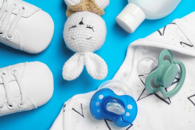 Photo of Flat lay composition with pacifiers and other baby stuff on light blue background