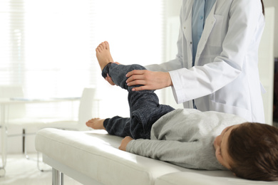 Professional orthopedist examining little patient's leg in clinic