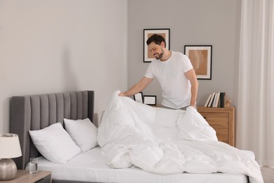 Photo of Man changing bed linens at home. Space for text