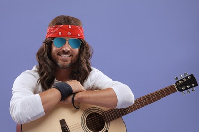 Photo of Stylish hippie man with guitar on violet background
