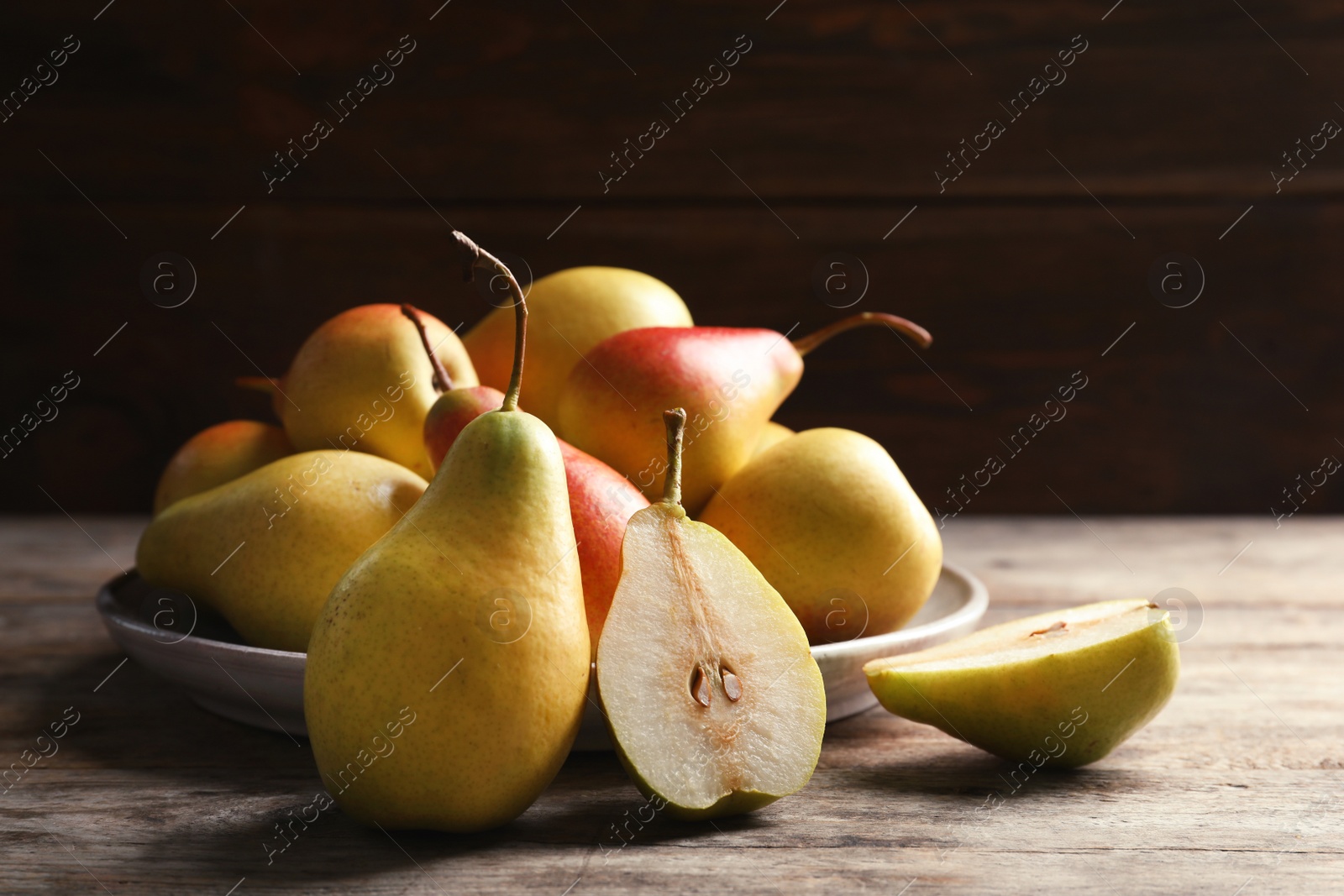 Photo of Ripe pears on wooden table against dark background