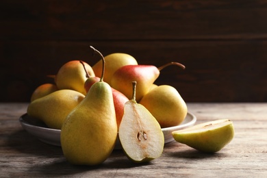 Photo of Ripe pears on wooden table against dark background