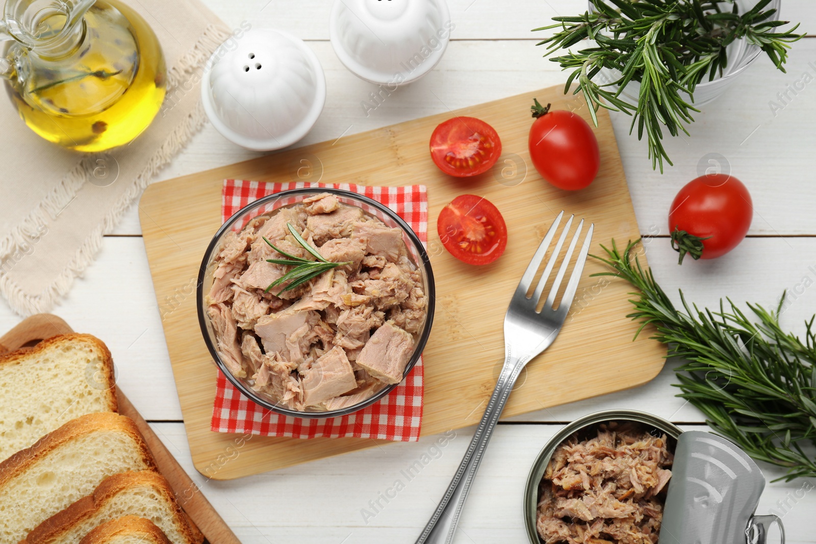 Photo of Bowl with canned tuna and products on white wooden table, flat lay