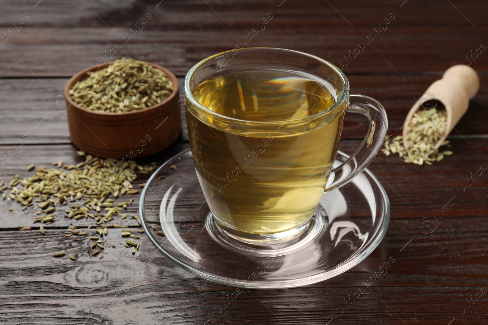 Photo of Aromatic fennel tea and seeds on wooden table, closeup