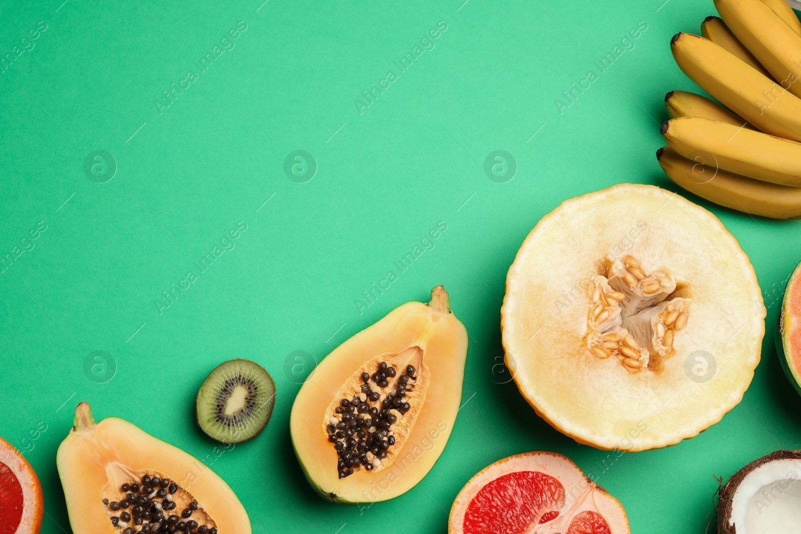 Photo of Flat lay composition with tasty melon and fresh tropical fruits on green background, space for text