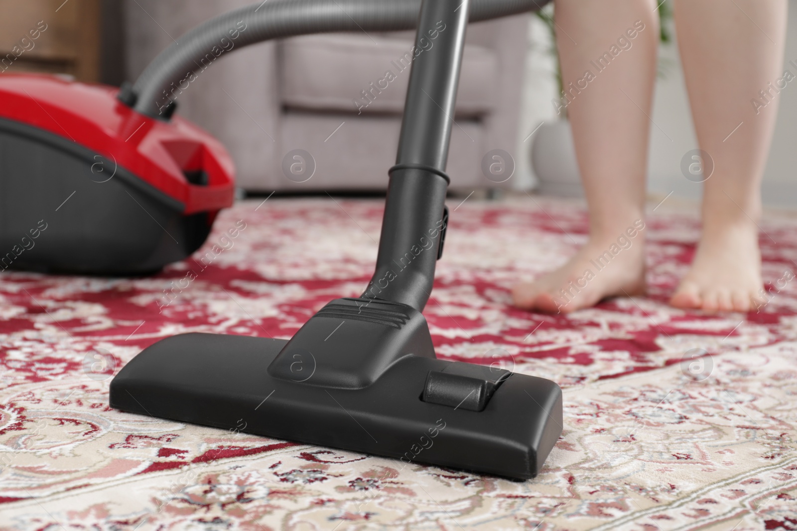 Photo of Woman cleaning carpet with vacuum cleaner at home, closeup