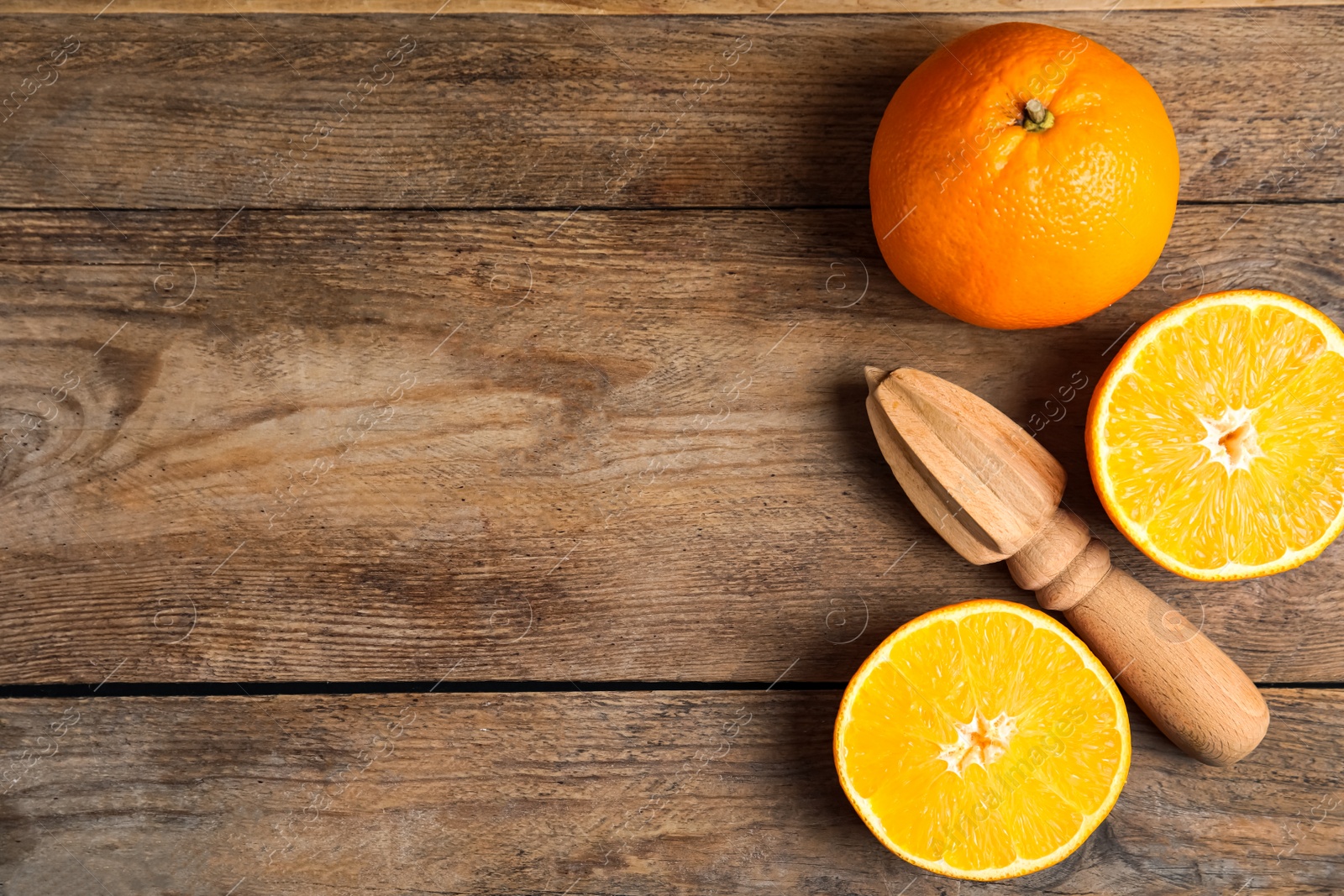 Photo of Fresh ripe oranges and reamer on wooden table, flat lay. Space for text