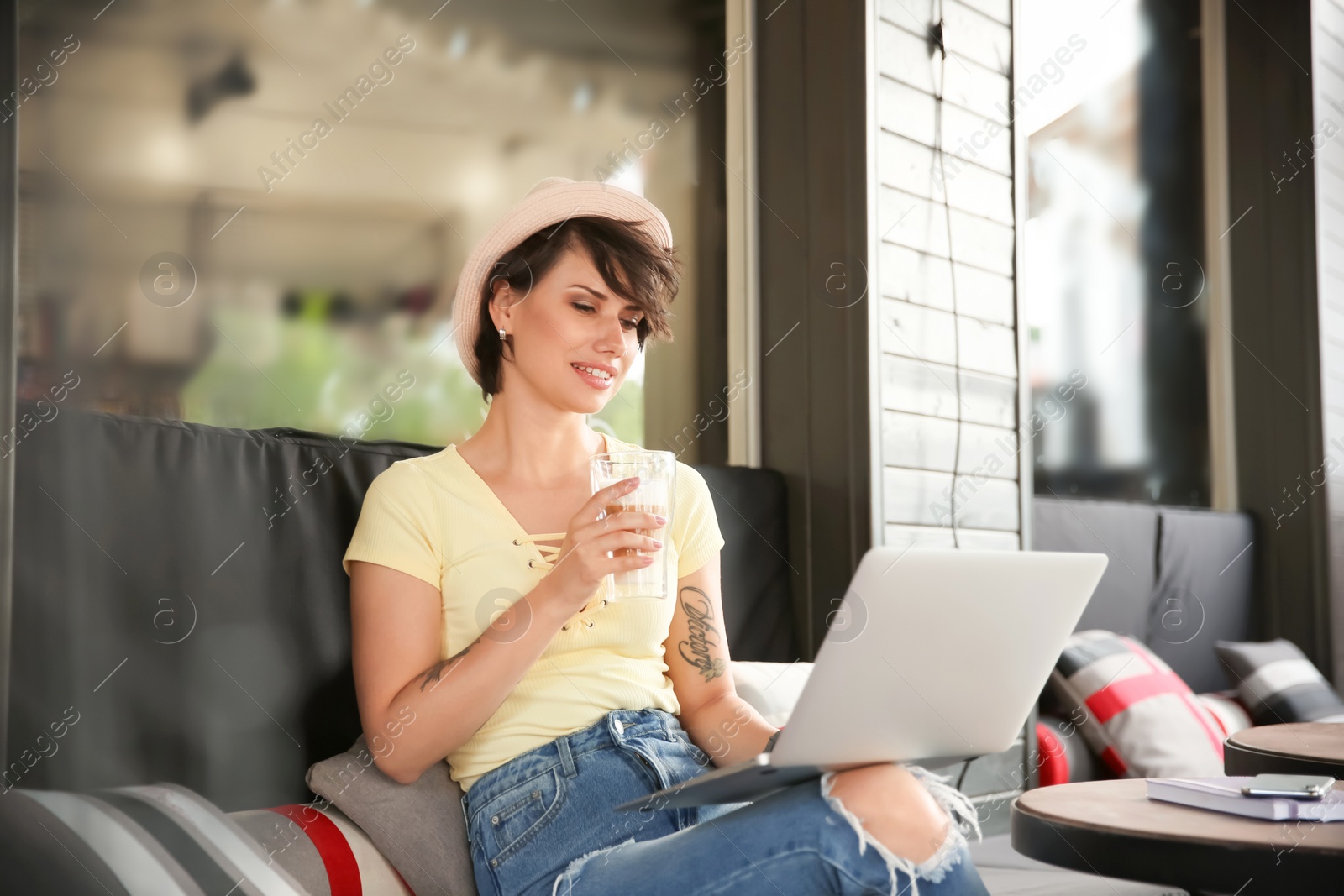 Photo of Young woman working with laptop in cafe