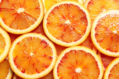 Juicy blood orange slices as background, top view. Citrus fruit