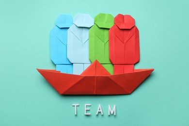 Photo of Many colorful paper figures in boat and word Team on light blue background, flat lay. Recruiter searching employee