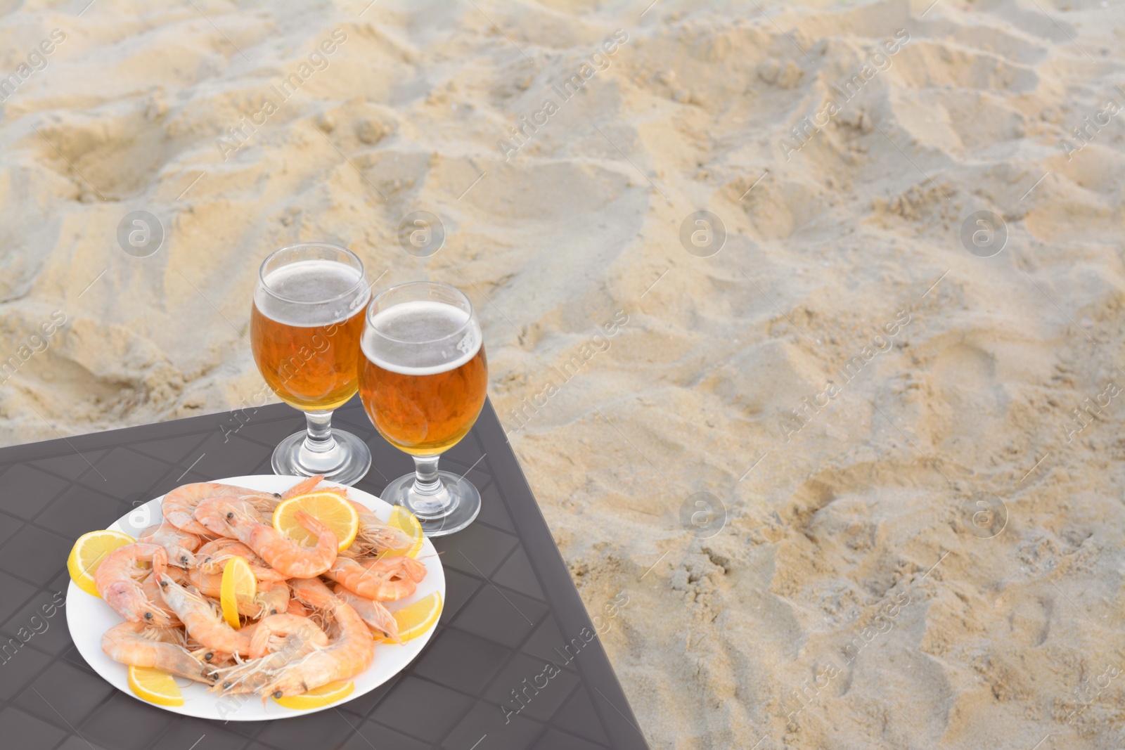 Photo of Cold beer in glasses and shrimps served with lemon on beach