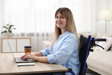 Photo of Woman in wheelchair using laptop at table in home office