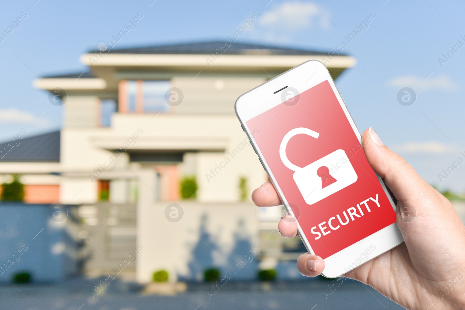 Image of Home security system. Woman with smartphone near her house outdoors, closeup