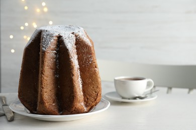 Photo of Delicious Pandoro cake decorated with powdered sugar on white wooden table, space for text. Traditional Italian pastry