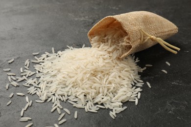 Photo of Raw basmati rice and overturned sack on black table