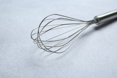 Photo of Metal whisk on gray table, closeup. Kitchen tool