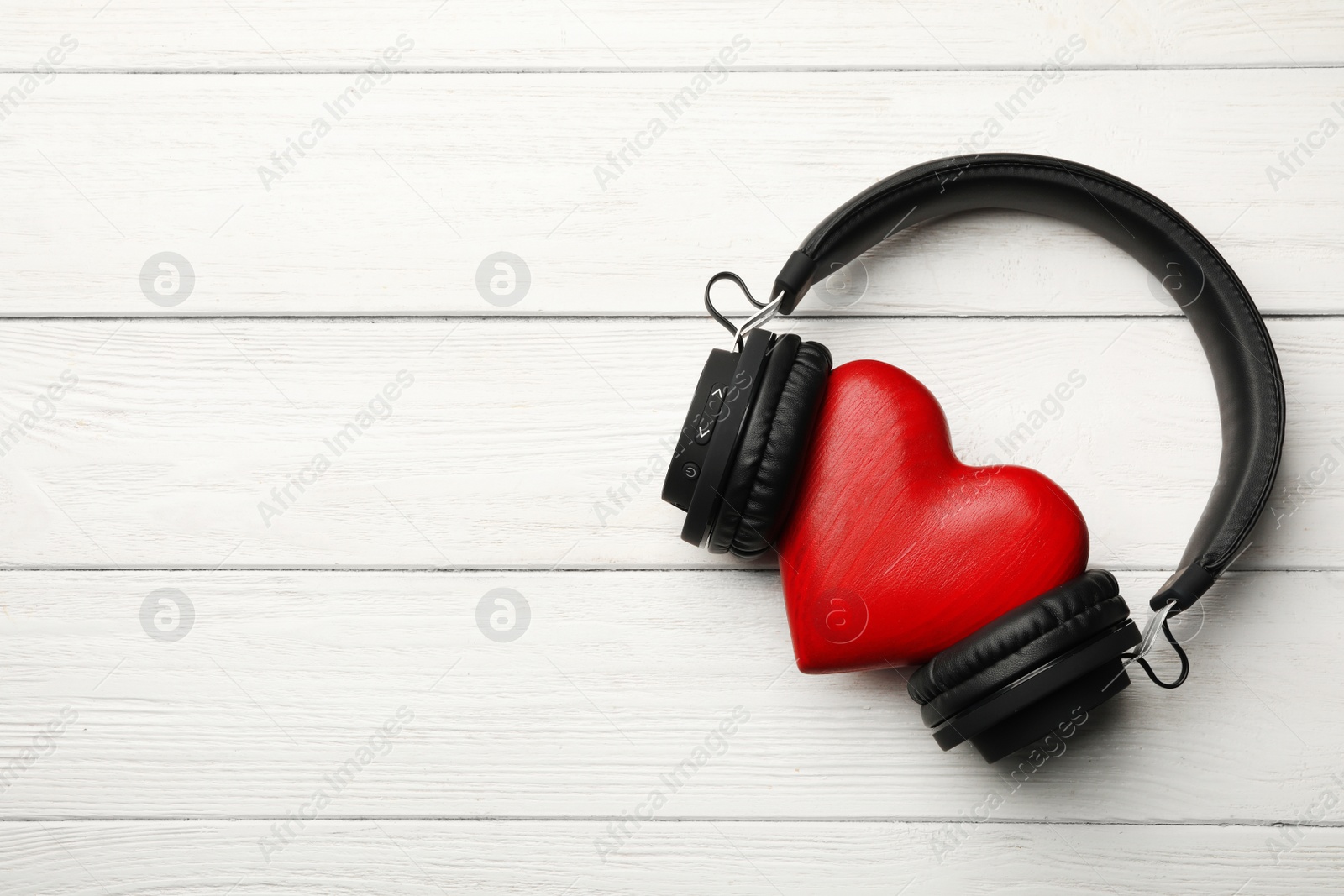 Photo of Decorative heart with modern headphones on wooden background, top view. Space for text