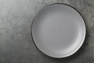 Photo of Empty ceramic plate on grey table, top view. Space for text