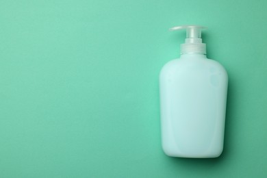 Photo of Bottle of liquid soap on turquoise background, top view. Space for text