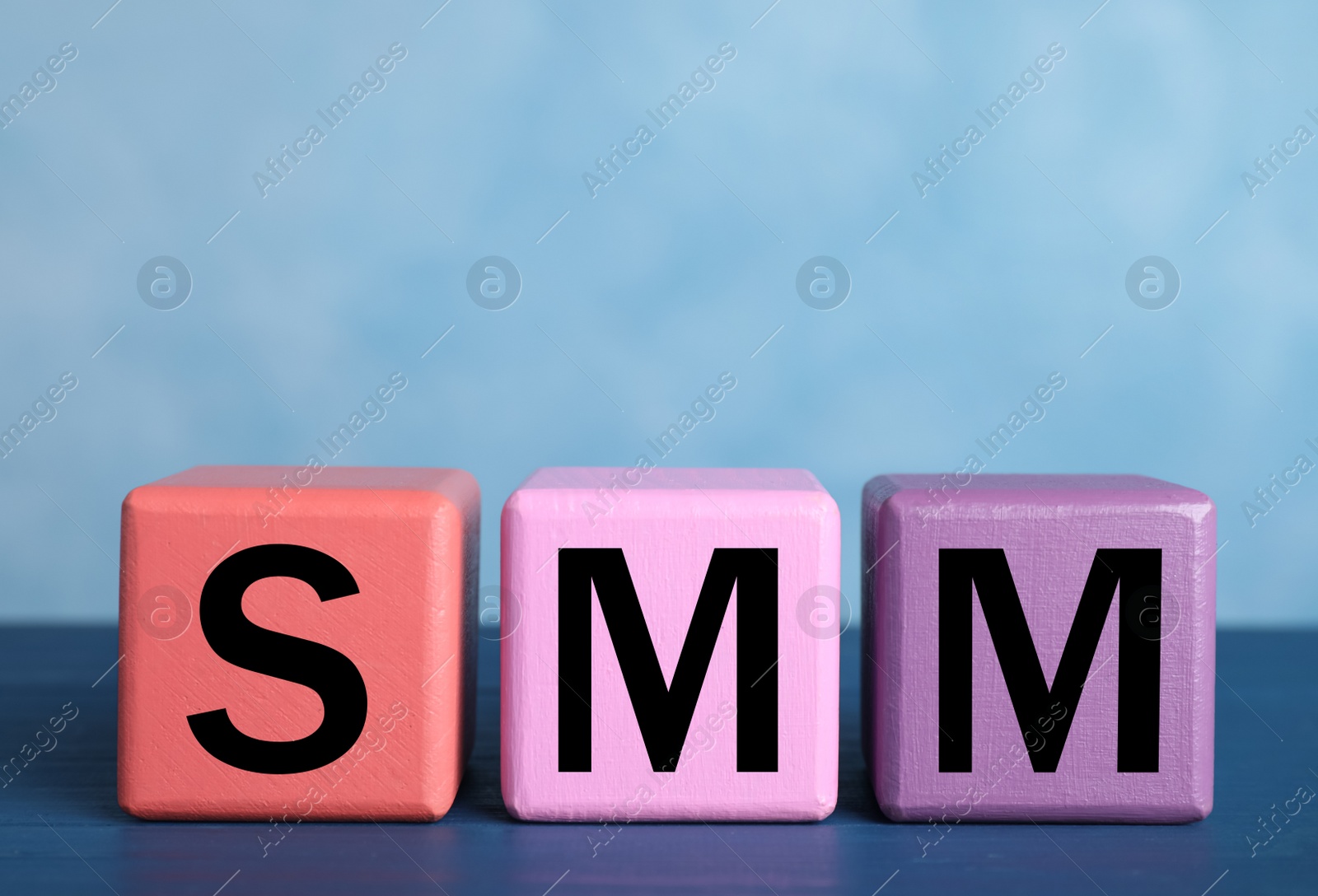 Photo of Colorful cubes with abbreviation SMM (Social media marketing) on blue table