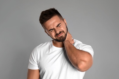 Photo of Man suffering from neck pain on light grey background