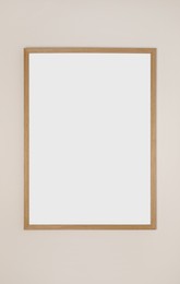 Photo of Blank frame hanging on light wall. Space for design