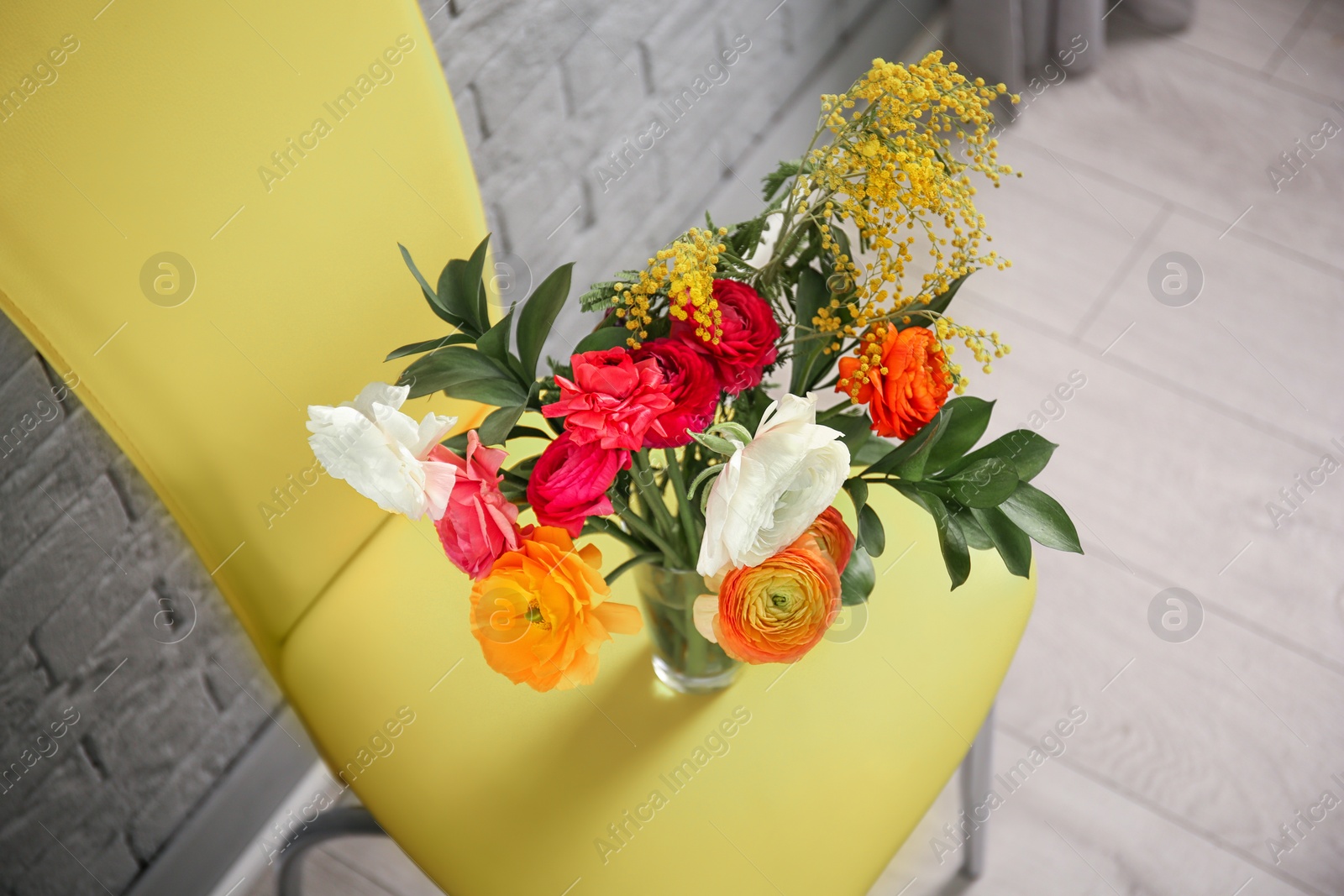 Photo of Vase with beautiful ranunculus flowers on chair indoors